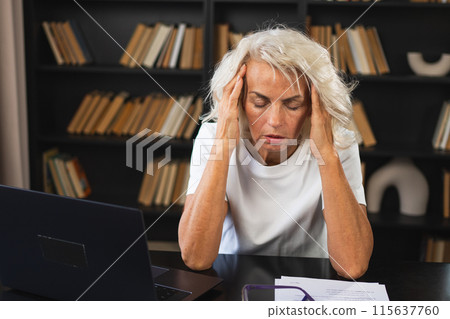 Headache pain. Middle aged woman touching temples experiencing stress. Mature old lady tired of work feeling headache sick rubbing temples forehead. Long laptop usage computer vision office syndrome Headache pain. Middle aged woman touching temples experiencing stress. Mature old lady tired of work feeling headache sick rubbing temples forehead. Long laptop usage computer vision office syndrome 115637760