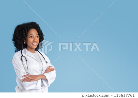 Happy young black woman doctor therapist in white coat with crossed arms on chest looks at free space, isolated on blue studio background. Ad and offer, professional recommendation, health care Happy young black woman doctor therapist in white coat with crossed arms on chest looks at free space, isolated on blue studio background. Ad and offer, professional recommendation, health care 115637761