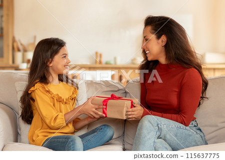 Surprise Gift For Daughter On Birthday. Cheerful Arab Mom Giving Wrapped Present Box To Preteen Daughter, Sitting On Sofa, Congratulating And Celebrating Family Holiday At Home Surprise Gift For Daughter On Birthday. Cheerful Arab Mom Giving Wrapped Present Box To Preteen Daughter, Sitting On Sofa, Congratulating And Celebrating Family Holiday At Home 115637775