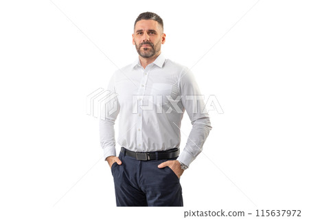 A man dressed in a crisp white shirt and dark trousers stands confidently with hands in pockets, looking directly ahead. He is captured against a plain white backdrop 115637972