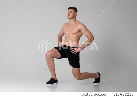 A man is exercising by performing squats on a gray background. He is bending his knees and lowering his hips, then pushing back up to a standing position 115638235