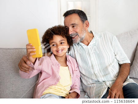 Multigenerational Mobile Fun. Joyful Grandpa and Little Grandson Making Selfie Together Via Smartphone, Sharing Bonding Moments In Social Media Application, Sitting On Couch At Home 115638604