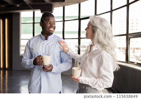 Corporate Lifestyle And Communication. Multiethnic Business Colleagues Enjoying Coffee Break, Talking Holding Mugs, Lady Touching Man's Shoulder Communicating In Office Interior Corporate Lifestyle And Communication. Multiethnic Business Colleagues Enjoying Coffee Break, Talking Holding Mugs, Lady Touching Man's Shoulder Communicating In Office Interior 115638649
