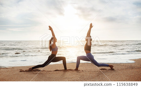 Calm cheerful young caucasian women enjoy morning workout, breathing exercises, practicing yoga on sea beach, panorama, profile. Weight loss, sports outdoor, lifestyle and body care 115638849
