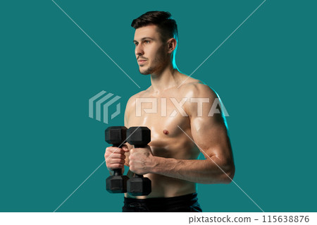A man is standing and holding a pair of dumbbells in his hands. The background is a solid green color, emphasizing the focus on the man and the weights he is holding. 115638876
