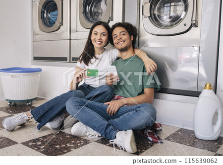 Laundry Offer. Happy Young Couple Showing Credit Card Sitting Near New Washing Machines, Using Smartphone Enjoying Self Service And Smiling To Camera. Enjoy Household Leisure Together Laundry Offer. Happy Young Couple Showing Credit Card Sitting Near New Washing Machines, Using Smartphone Enjoying Self Service And Smiling To Camera. Enjoy Household Leisure Together 115639062