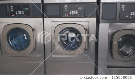 Public Laundry Service. Background With Three Industrial Washing Machines In Laundromat Room Standing In A Row Indoors. Laundrette Equipment And Technology Concept. Panorama Public Laundry Service. Background With Three Industrial Washing Machines In Laundromat Room Standing In A Row Indoors. Laundrette Equipment And Technology Concept. Panorama 115639096