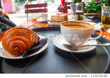 Breakfast view a bunch of croissant and a cup of coffee with cafe vibe background. Breakfast view a bunch of croissant and a cup of coffee with cafe vibe background. 115639186