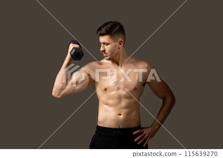 A shirtless man is seen holding a dumbbell in a gym setting. He appears focused and engaged in his workout routine, displaying strength and determination. A shirtless man is seen holding a dumbbell in a gym setting. He appears focused and engaged in his workout routine, displaying strength and determination. 115639270
