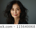 Close up of middle-age asian woman in black suit against blank grey background for advertising 115640068