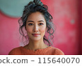 Asian middle-age woman with grey hair in orange sweater against textured pink background for ads 115640070