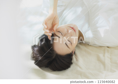 Woman lying on bed 115640082