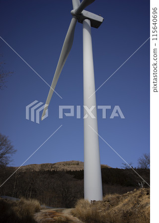 Wind turbines towering over a clear blue sky 115640696