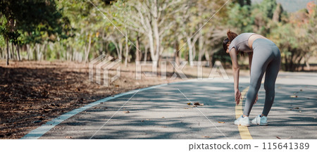 Woman in active wear stretching on a park path during an autumn morning, promoting fitness and a healthy lifestyle. Woman in active wear stretching on a park path during an autumn morning, promoting fitness and a healthy lifestyle. 115641389