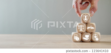 Wooden blocks with legal and medical icons arranged in a pyramid by a hand, representing personal injury law, legal protection, justice, and healthcare services. Wooden blocks with legal and medical icons arranged in a pyramid by a hand, representing personal injury law, legal protection, justice, and healthcare services. 115641410