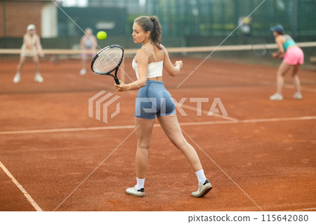 Emotional fit young girl playing doubles tennis on outdoor court 115642080