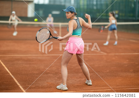 Emotional fit young girl playing doubles tennis on outdoor court 115642081