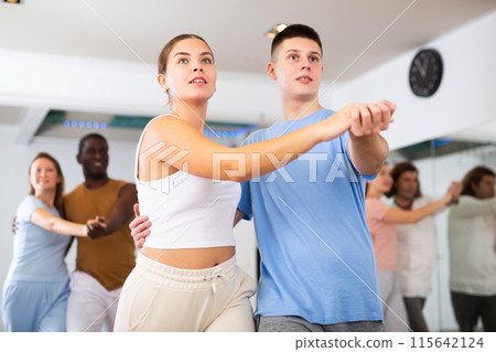 Woman and man practicing bachata dance moves in pair during group modern class 115642124