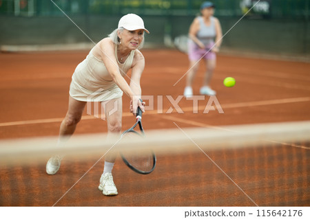 Two elderly women playing doubles tennis 115642176