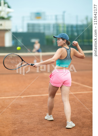 Young woman making serve while playing tennis 115642177
