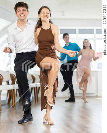 Cheerful young couple dancing vigorous lindy hop at group rehearsal Cheerful young couple dancing vigorous lindy hop at group rehearsal 115642355