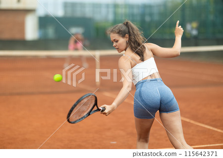 Young woman making serve while playing tennis Young woman making serve while playing tennis 115642371