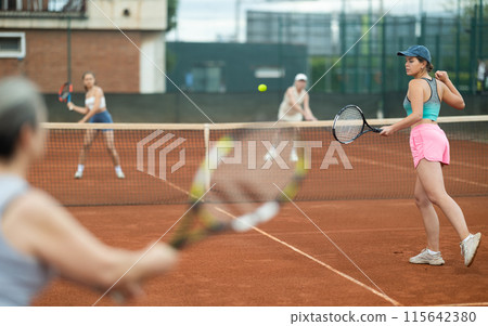 Sporty young girl playing doubles tennis on outdoor court 115642380