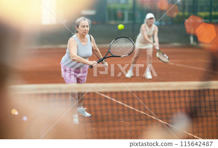 Two elderly women playing doubles tennis Two elderly women playing doubles tennis 115642487
