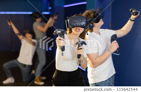 Young guy and girl in vr headset stand shoulder to shoulder interacting with digital interface Young guy and girl in vr headset stand shoulder to shoulder interacting with digital interface 115642544