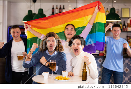 Group of friends waving LGBT flag during rest in pub Group of friends waving LGBT flag during rest in pub 115642545