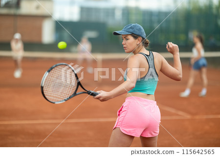 Emotional fit young girl playing doubles tennis on outdoor court 115642565