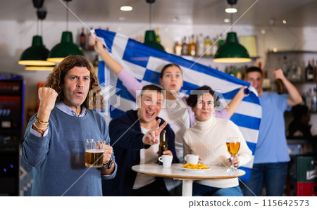 Enthusiastic Greek fans scream with joy in beer bar. Greece win Enthusiastic Greek fans scream with joy in beer bar. Greece win 115642573