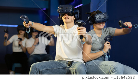 friends in helmets and with joysticks are sitting playing 3d action game. entertainment club friends in helmets and with joysticks are sitting playing 3d action game. entertainment club 115642588