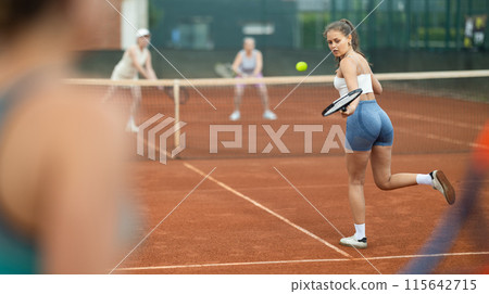 Young woman playing tennis against elderly women 115642715