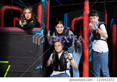 Two girls and two guys posing with lasertag guns in arena Two girls and two guys posing with lasertag guns in arena 115642872