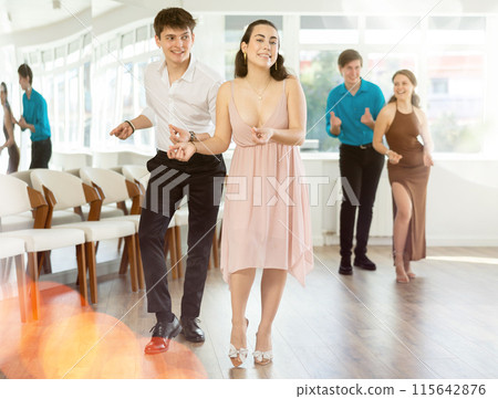 Couple in evening dresses enjoys pair dance boogie-woogie, interacting with each other on floor 115642876