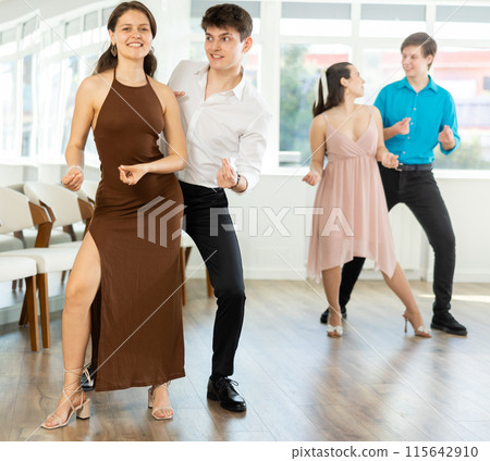 Couple in evening dresses enjoys pair dance boogie-woogie, interacting with each other on floor 115642910