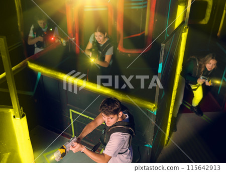 Team of young people play laser tag in labyrinth. View from above Team of young people play laser tag in labyrinth. View from above 115642913