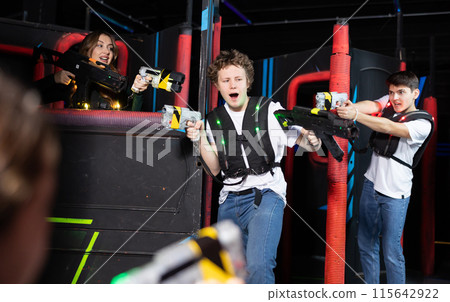 Three people having fun playing lasertag in arena Three people having fun playing lasertag in arena 115642922