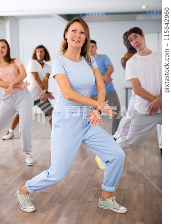 Females and males doing dance workout during group classes in fitness center 115642960