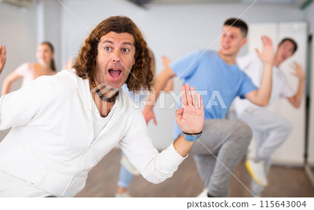 Men and women having dance training in modern studio, performing contemporary dance elements Men and women having dance training in modern studio, performing contemporary dance elements 115643004