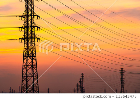 A row of power transmission towers and a sunset sky with thin clouds spreading out. c-3 Warm colors, high contrast 115643473