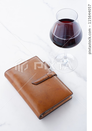 brown leather organizer and glass of red wine brown leather organizer and glass of red wine 115644057