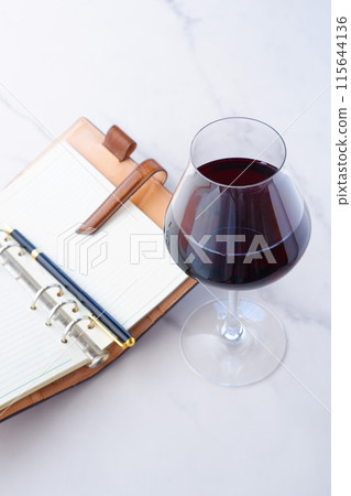 Image of a person writing a diary in a ring-type organizer while drinking red wine Image of a person writing a diary in a ring-type organizer while drinking red wine 115644136