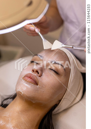 A girl at a cosmetologist does cosmetic procedures. Skin cleansing 115644283