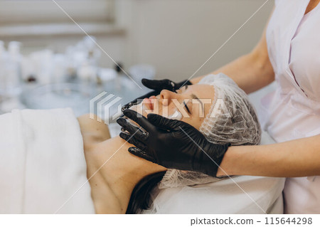 woman at the cosmetologist. She has problem skin and acne. 115644298