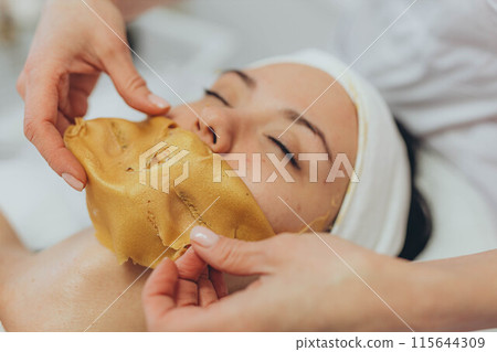 A girl at a cosmetologist does cosmetic procedures. Alginate mask 115644309