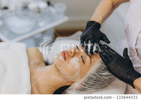 woman at the cosmetologist. She has problem skin and acne. 115644315