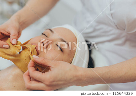 A girl at a cosmetologist does cosmetic procedures. Alginate mask A girl at a cosmetologist does cosmetic procedures. Alginate mask 115644329