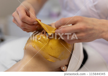 A girl at a cosmetologist does cosmetic procedures. Alginate mask A girl at a cosmetologist does cosmetic procedures. Alginate mask 115644345